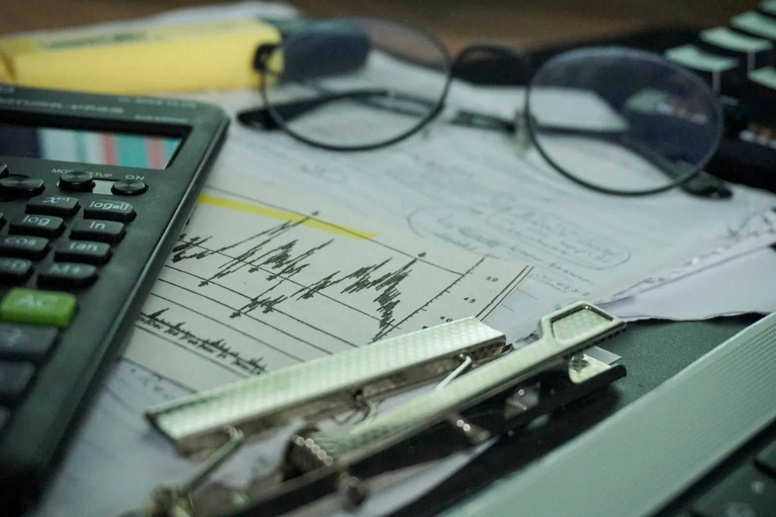 Calculator, financial report and eyeglasses on an analyst desk