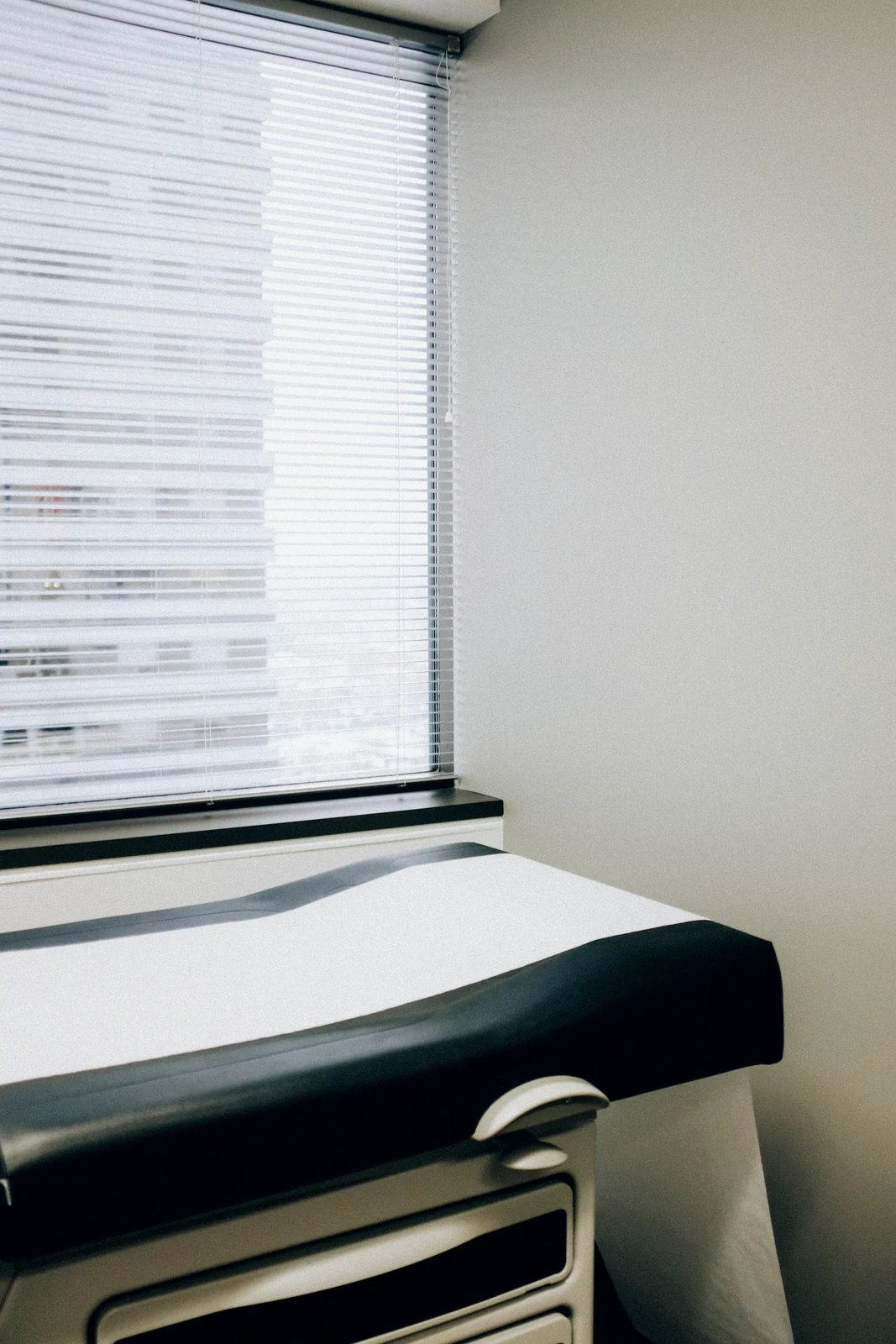 Clean medical examination room with a table beside a window